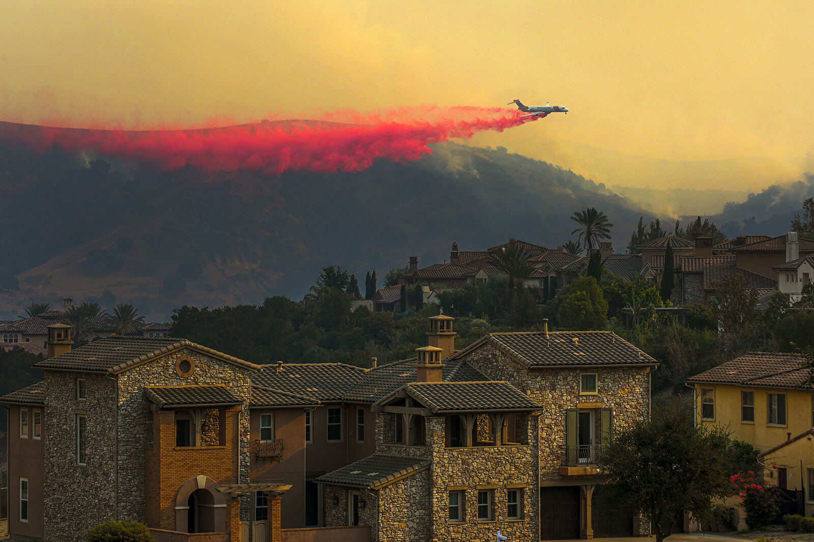 An air tanker drops fire retardant during a wildfire in 2020 in Chino Hills, where home are strewn across a pastoral landscape that drew people to the area.